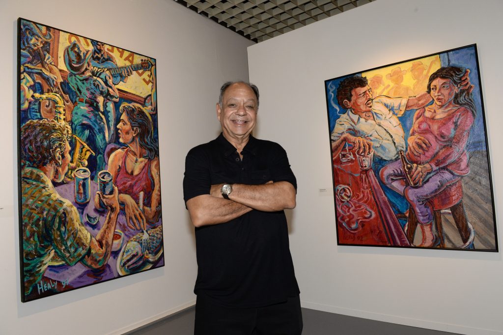 Cheech Marin poses in front of a painting by US artist Wayne Alaniz Healy on June 26, 2014 at the Aquitaine museum in Bordeaux. Photo by Mehdi Fedouach/AFP via Getty Images.